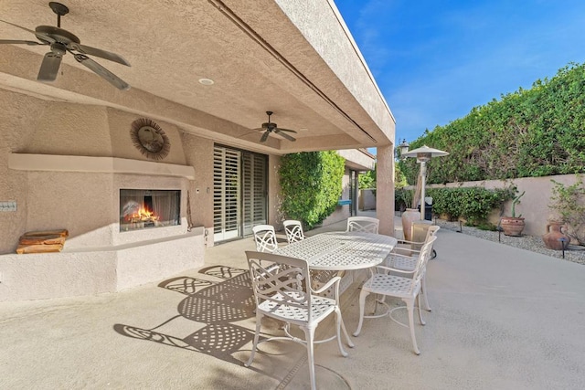 view of patio with ceiling fan and an outdoor fireplace