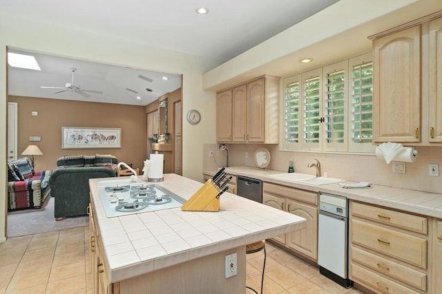 kitchen with ceiling fan, sink, stainless steel dishwasher, tile countertops, and light brown cabinetry