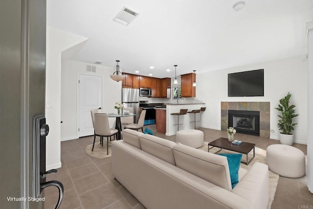 living room featuring a fireplace, light tile patterned floors, and sink