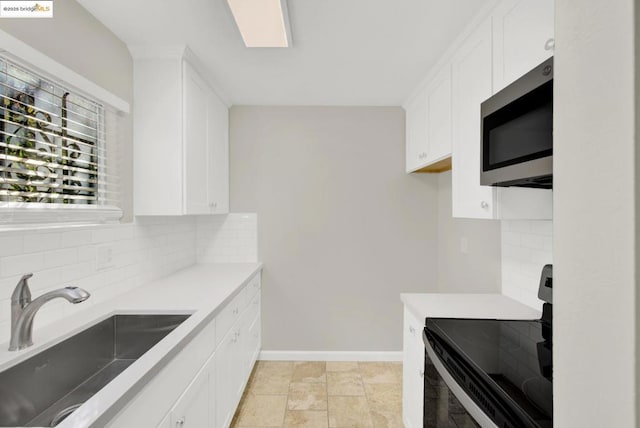 kitchen with decorative backsplash, black electric range, white cabinets, and sink