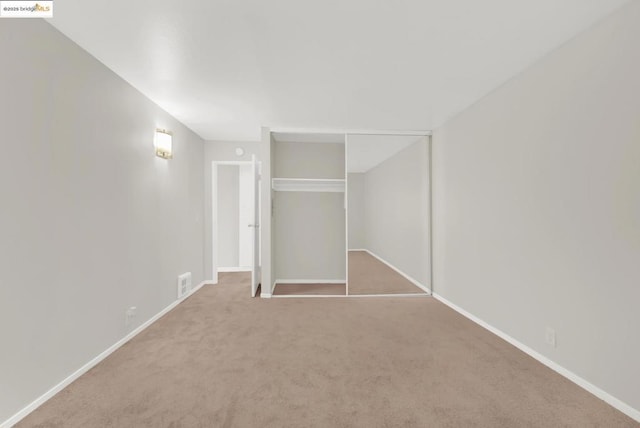 unfurnished bedroom featuring light colored carpet and a closet