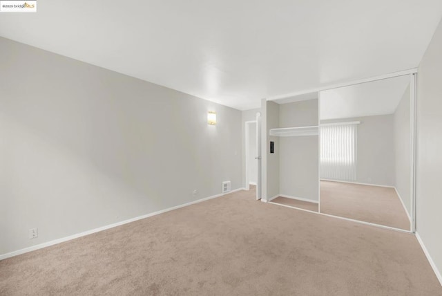 unfurnished bedroom featuring a closet and light colored carpet