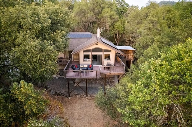 rear view of property with solar panels and a deck