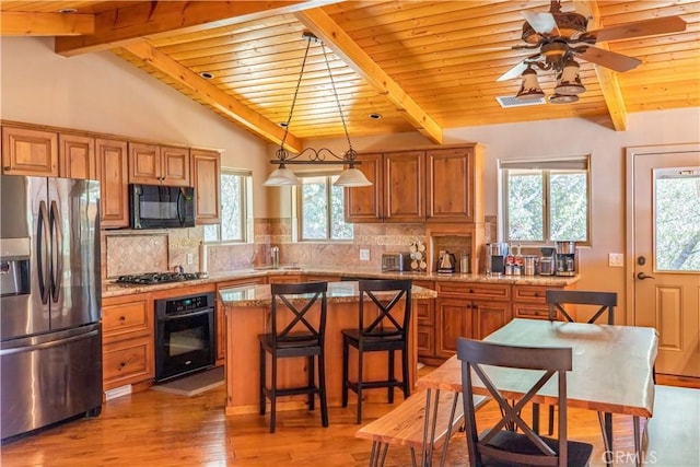 kitchen featuring decorative backsplash, a center island, black appliances, and decorative light fixtures