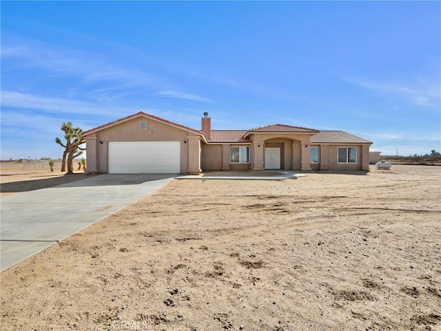 7755 7th St, Phelan, CA 92371 - view of front of property featuring a garage, a tile roof, a chimney, concrete driveway, and stucco siding