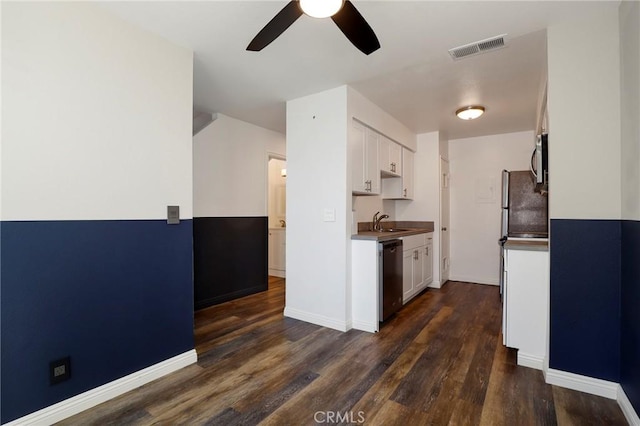 kitchen featuring appliances with stainless steel finishes, ceiling fan, dark wood-type flooring, sink, and white cabinets