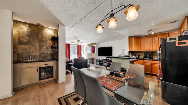 kitchen with dark countertops, wine cooler, freestanding refrigerator, light wood-style floors, and backsplash