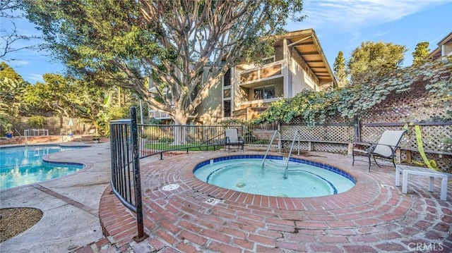 pool featuring a community hot tub, a fenced backyard, and a patio