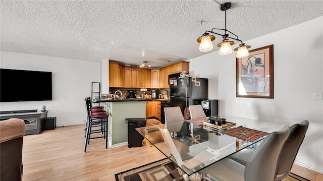 dining area with light wood-type flooring and a textured ceiling