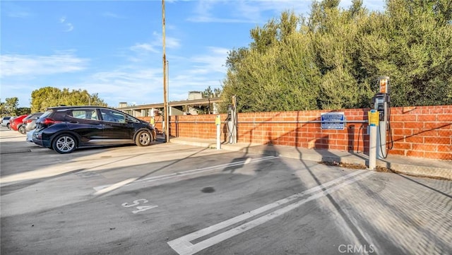 uncovered parking lot featuring a gate and fence