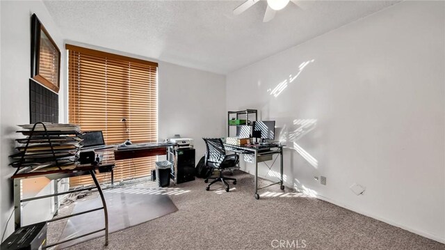 home office featuring carpet floors, ceiling fan, and a textured ceiling