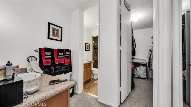 interior space featuring a spacious closet, a textured ceiling, and vanity