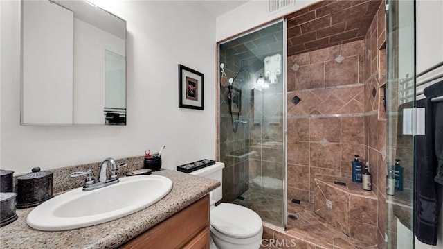 bathroom featuring a shower with shower door, toilet, and vanity