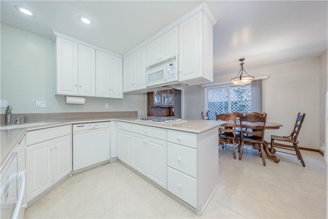 kitchen with a peninsula, white appliances, a sink, white cabinetry, and light countertops