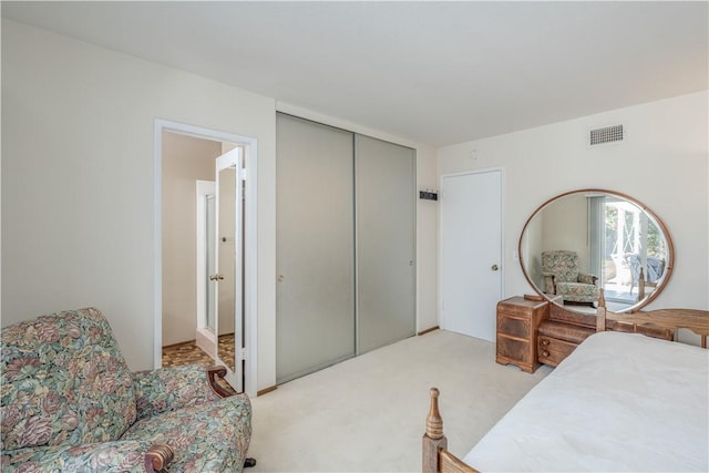 bedroom with a closet, visible vents, and light carpet