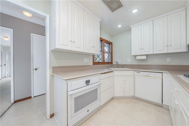 kitchen with white appliances, a sink, visible vents, and white cabinets