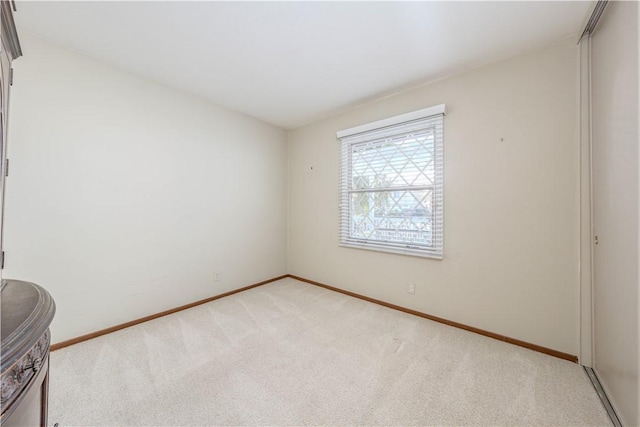 unfurnished room with light carpet and baseboards