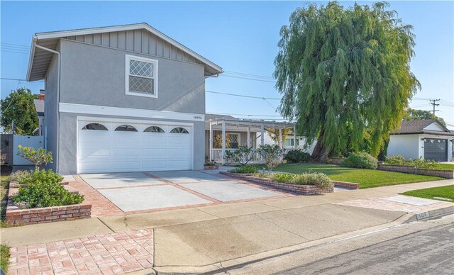 front facade featuring a garage, a front yard, and a pergola