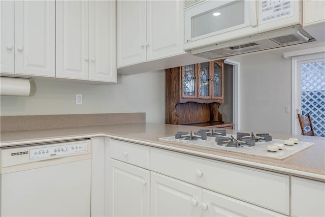 kitchen featuring white appliances, ventilation hood, white cabinets, and light countertops