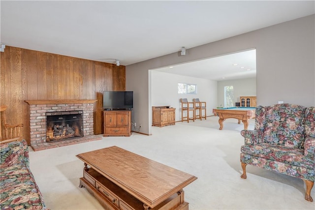 living room with carpet floors, a brick fireplace, pool table, and wooden walls