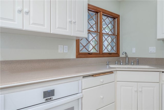 kitchen with white cabinets, light countertops, and a sink