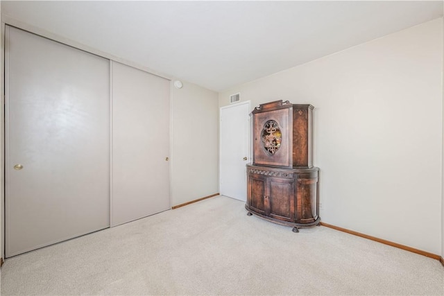 unfurnished bedroom featuring carpet floors, a closet, visible vents, and baseboards