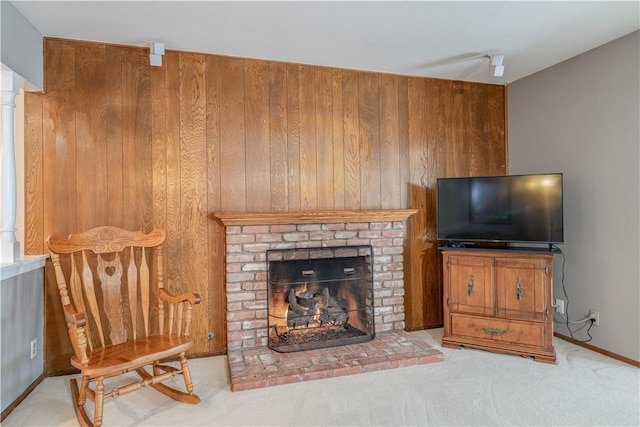 carpeted living room featuring a brick fireplace, wooden walls, and baseboards