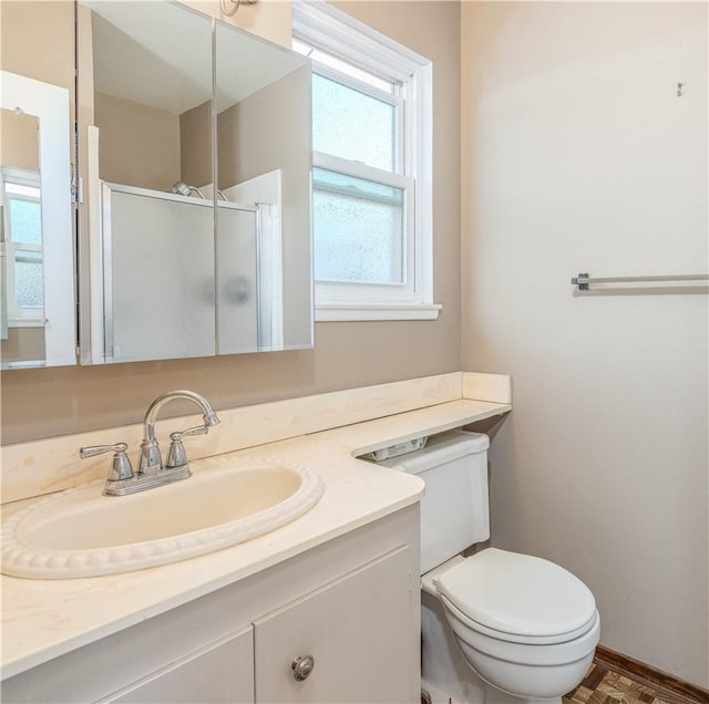 bathroom featuring toilet, a shower stall, and vanity