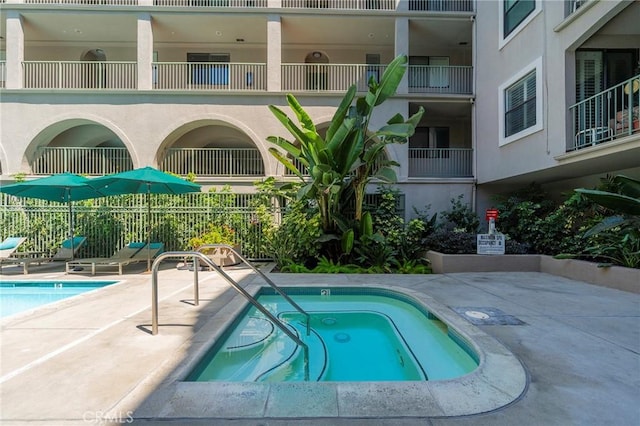 view of swimming pool featuring a hot tub and a patio