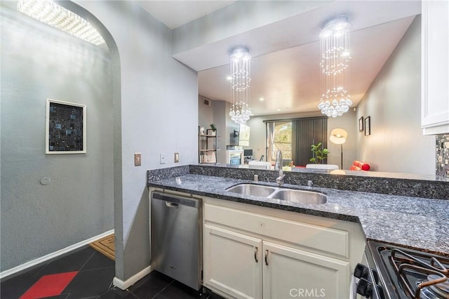 kitchen featuring pendant lighting, sink, appliances with stainless steel finishes, dark stone countertops, and a notable chandelier