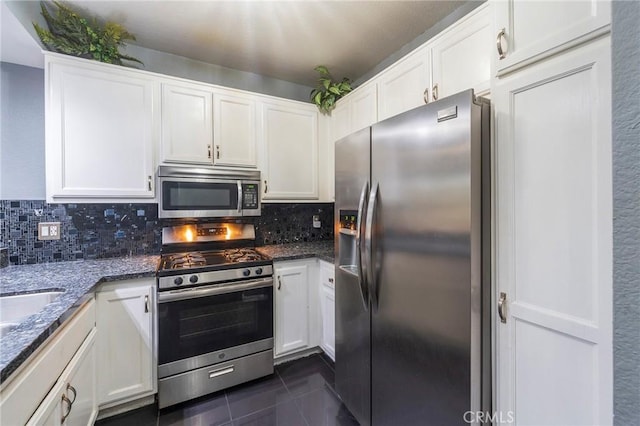 kitchen featuring white cabinetry, appliances with stainless steel finishes, tasteful backsplash, and dark stone counters