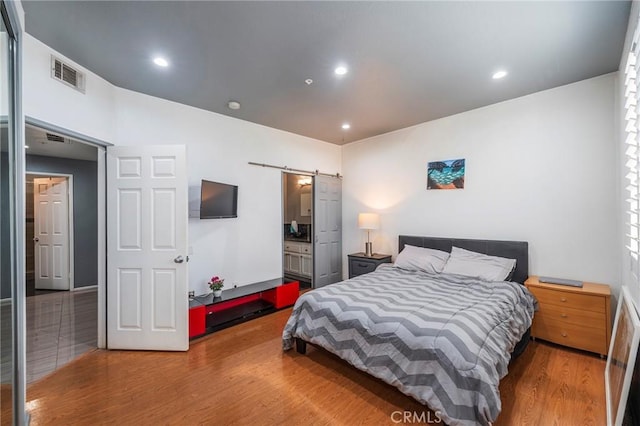 bedroom featuring hardwood / wood-style flooring and a barn door