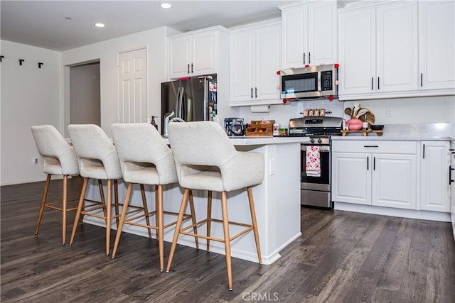 kitchen featuring a breakfast bar, appliances with stainless steel finishes, white cabinetry, and a kitchen island