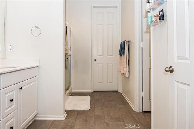 bathroom featuring a shower with door and vanity