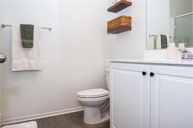 bathroom featuring a shower with door, vanity, and toilet