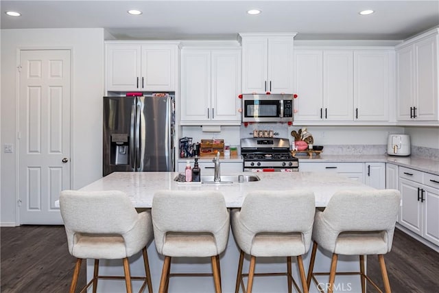 kitchen featuring light stone countertops, white cabinetry, stainless steel appliances, dark hardwood / wood-style floors, and a kitchen island with sink