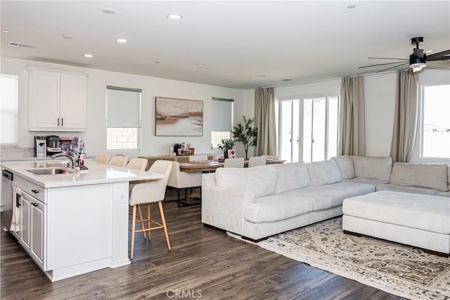 living room with dark hardwood / wood-style flooring, ceiling fan, and sink