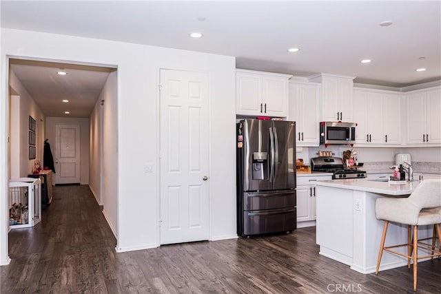 kitchen featuring a kitchen bar, a kitchen island, dark hardwood / wood-style flooring, white cabinetry, and stainless steel appliances