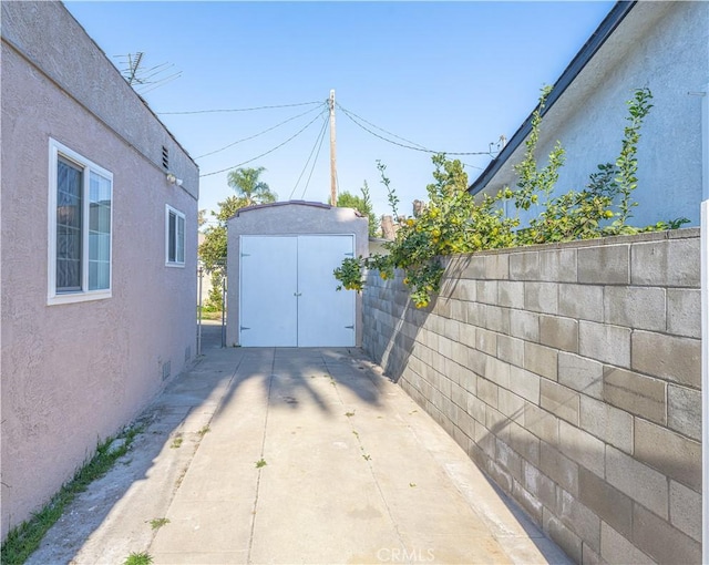 view of patio / terrace with an outbuilding, a shed, and fence