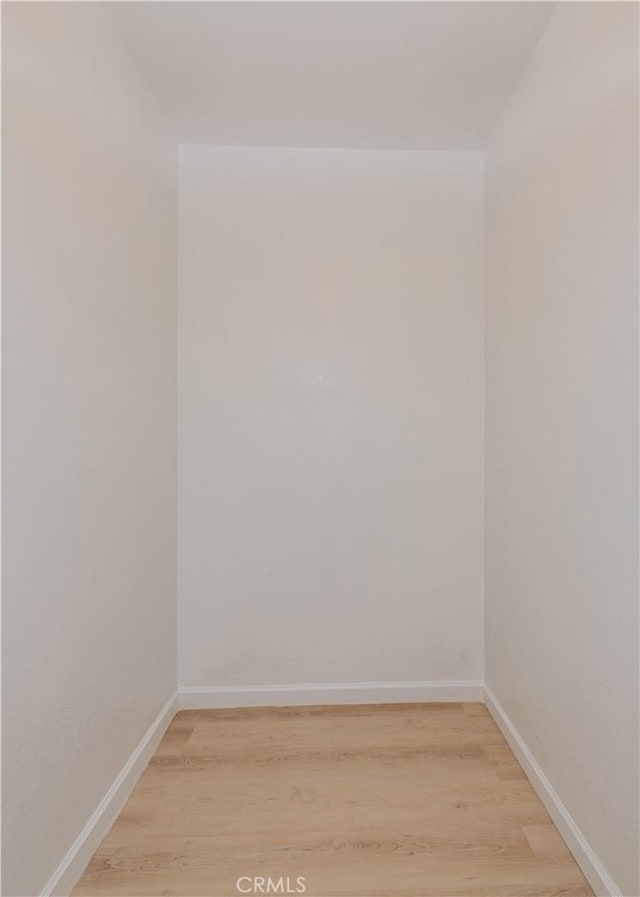 spare room with baseboards and light wood finished floors