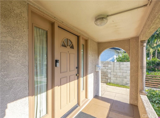 entrance to property featuring fence and stucco siding