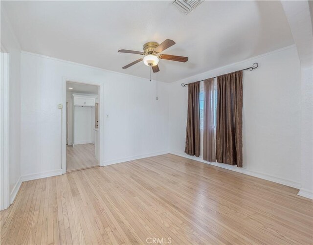 unfurnished room featuring visible vents, crown molding, baseboards, ceiling fan, and light wood-style flooring