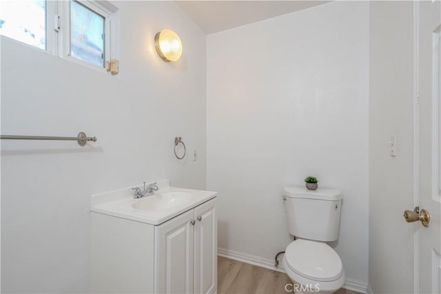 bathroom with baseboards, toilet, wood finished floors, and vanity