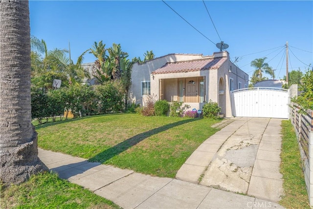 bungalow-style home with stucco siding, a gate, fence, a tiled roof, and a front lawn