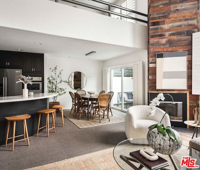 dining room featuring a large fireplace, carpet floors, and a high ceiling