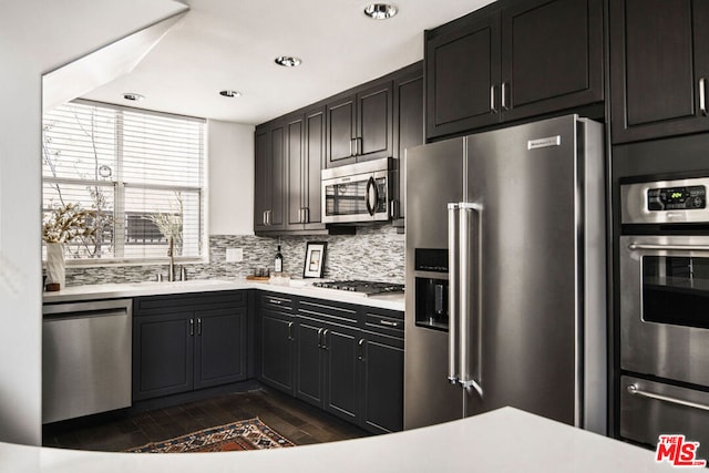 kitchen with decorative backsplash, appliances with stainless steel finishes, dark hardwood / wood-style flooring, and sink