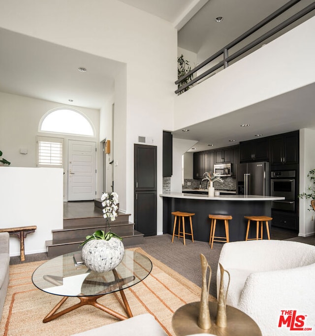 carpeted living room with a towering ceiling