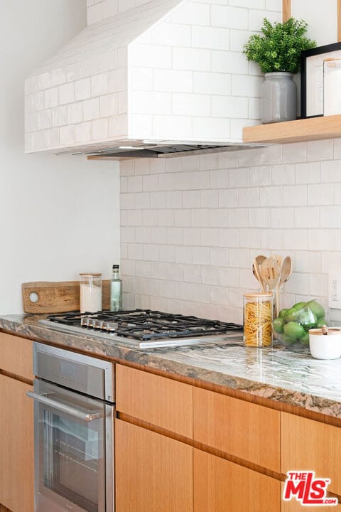 kitchen featuring backsplash, light stone countertops, and stainless steel appliances