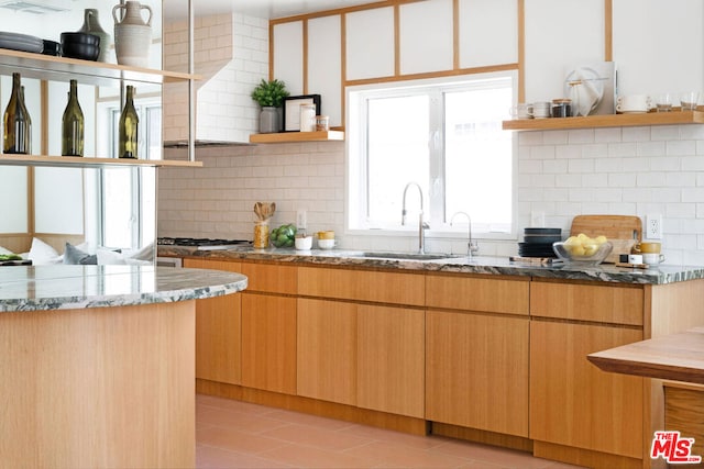 kitchen with sink, light stone countertops, light tile patterned floors, tasteful backsplash, and stainless steel gas cooktop