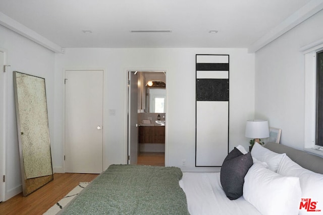 bedroom with connected bathroom and hardwood / wood-style flooring